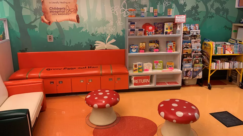 A colorful reading room with red bench seats an a bookcase full of children's books