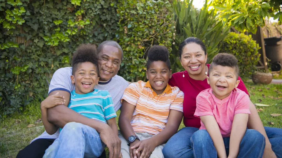 A man, a woman, and three young boys smile at the camera