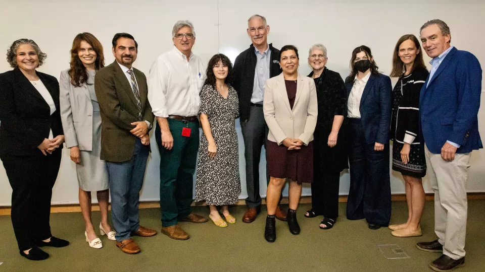 11 men and women stand and smile at the camera.