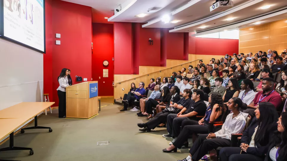 Two high school interns present their research to a full auditorium.