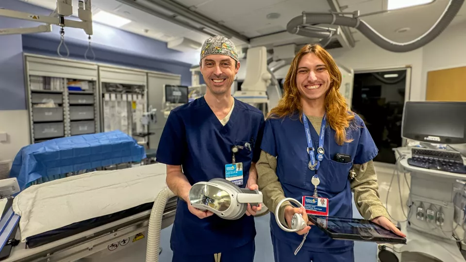 Dr. Miller and Phoenix hunt pose next to one another and smile while standing in the Interventional Radiology procedure room.