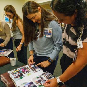 A group of event attendees look through commemorative photo albums together.