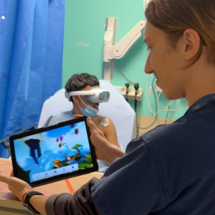 Hunt monitors the patient's view in VR using a tablet while the patient tries out the game in pre-op.