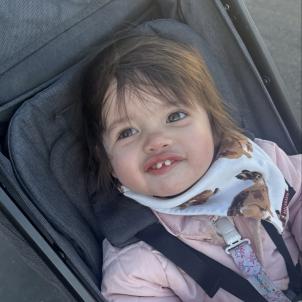 A toddler in a stroller looks upward and smiles.