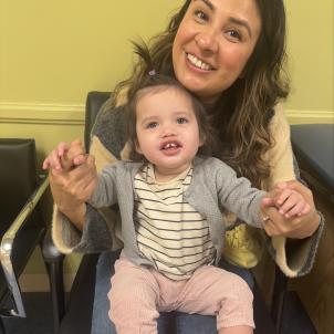 Toddler sits in her mother's lap at the doctor's office.