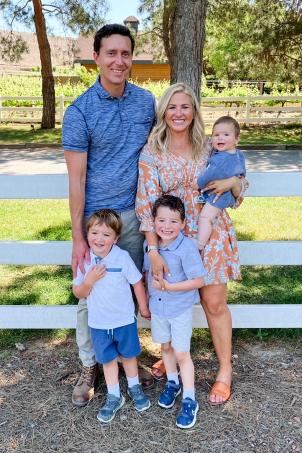 Male adult in blue shirt standing beside female adult and three small children