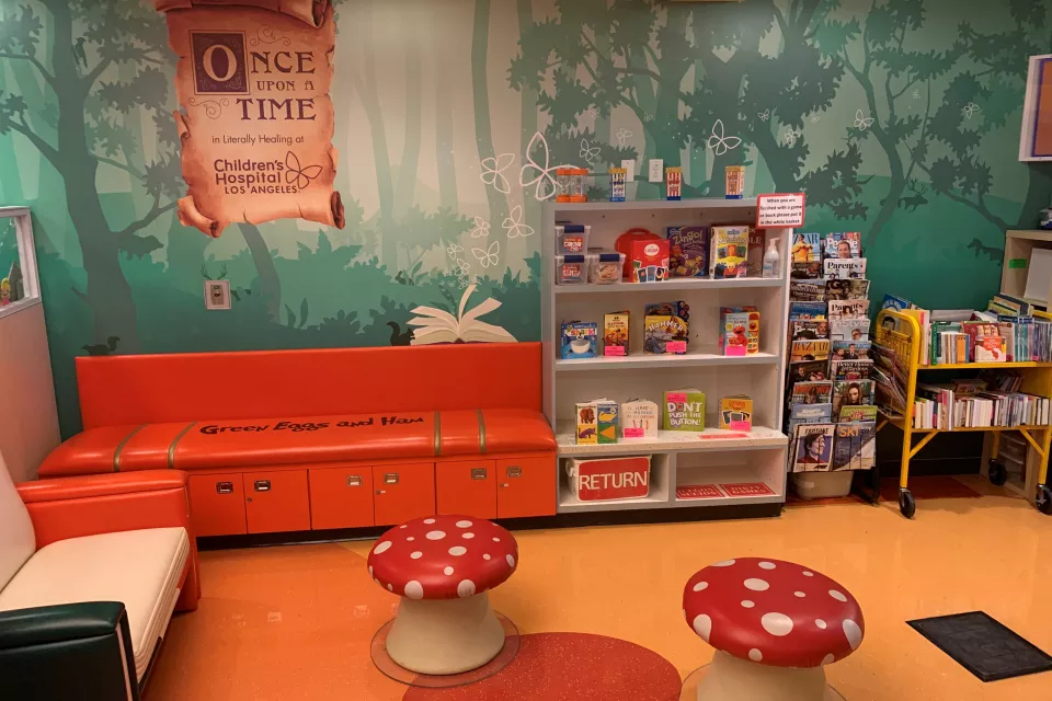 A colorful reading room with red bench seats an a bookcase full of children's books